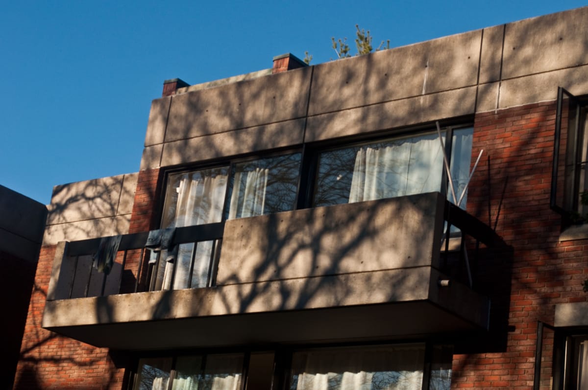 A Dakin dorm balcony, with the shadows of tree branches cast upon it.