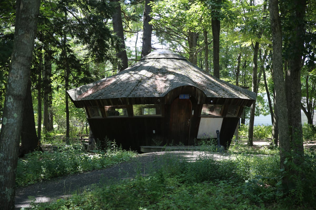 The Hampshire Yurt, a cylindrical building, surrounded by lush green trees.